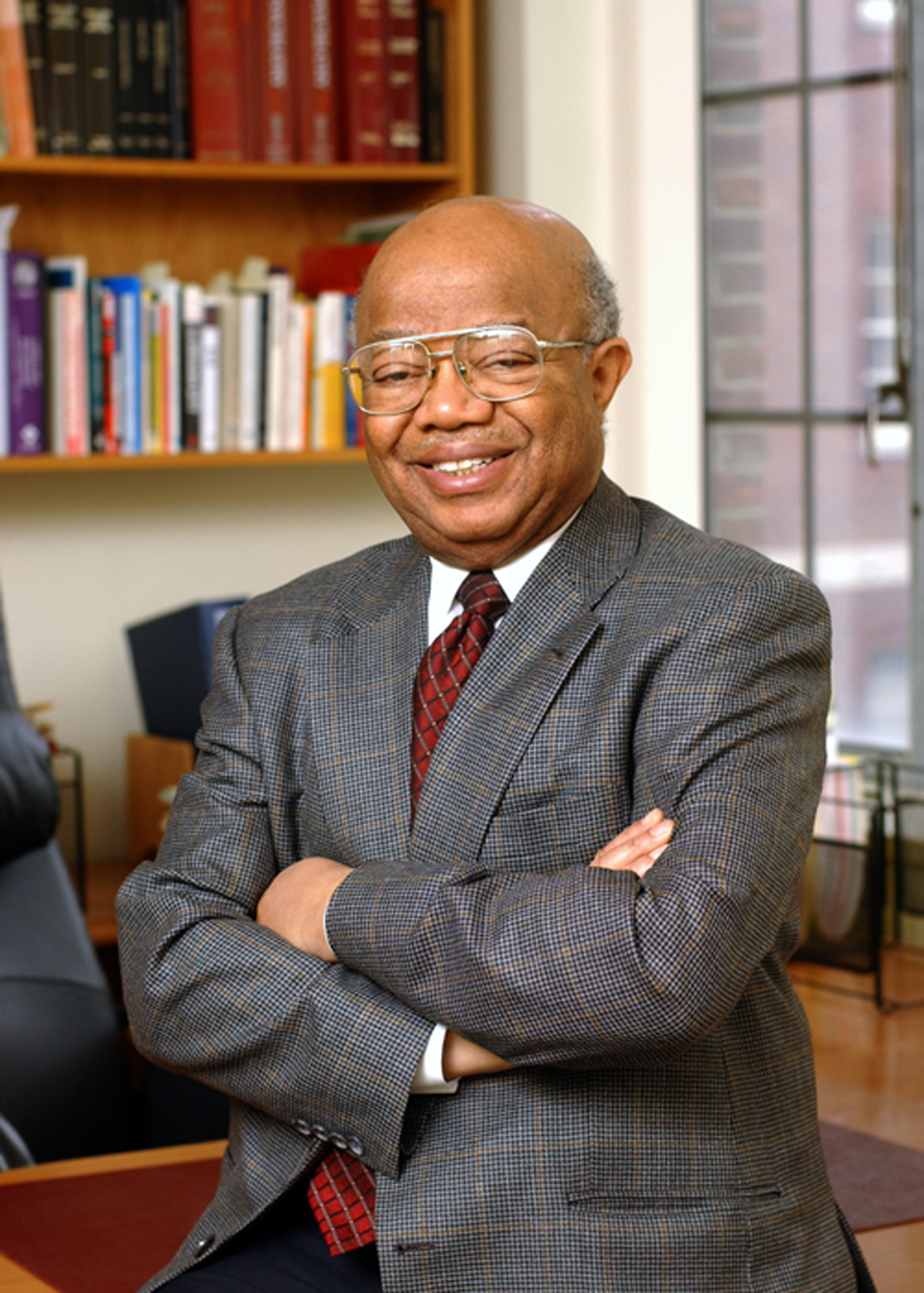 James Comer - older African American professor wearing a suit and tie and glasses in his office